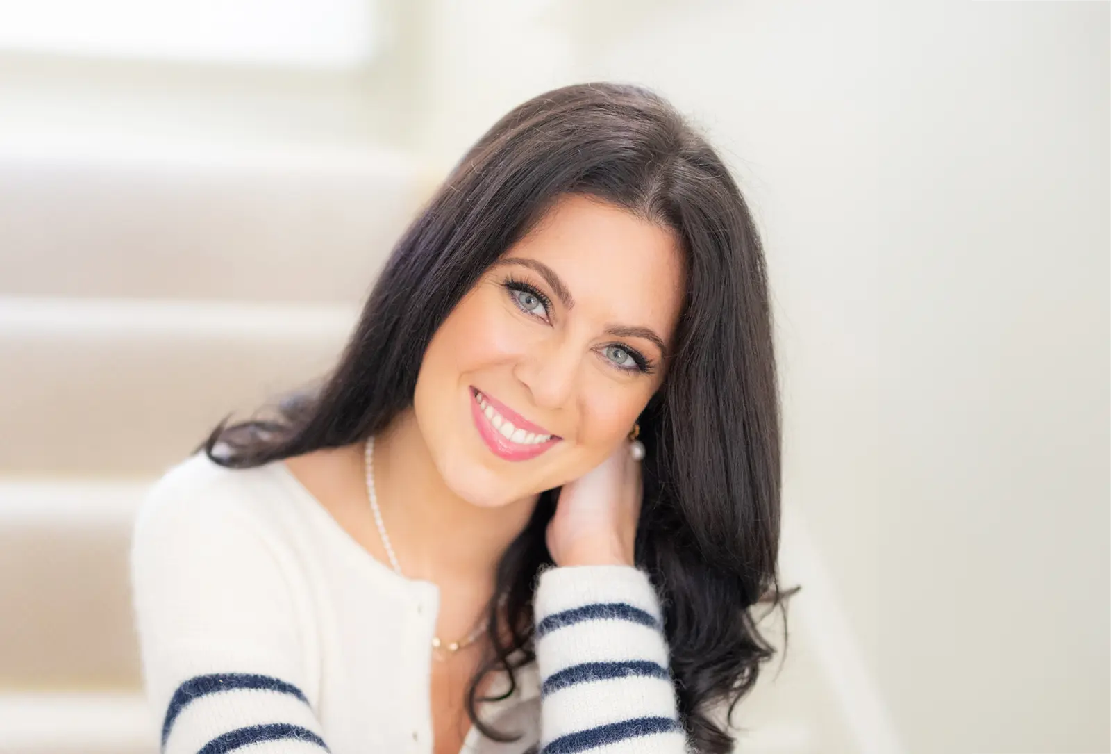 Headshot of Natasha in a white top with blue stripes, smiling.